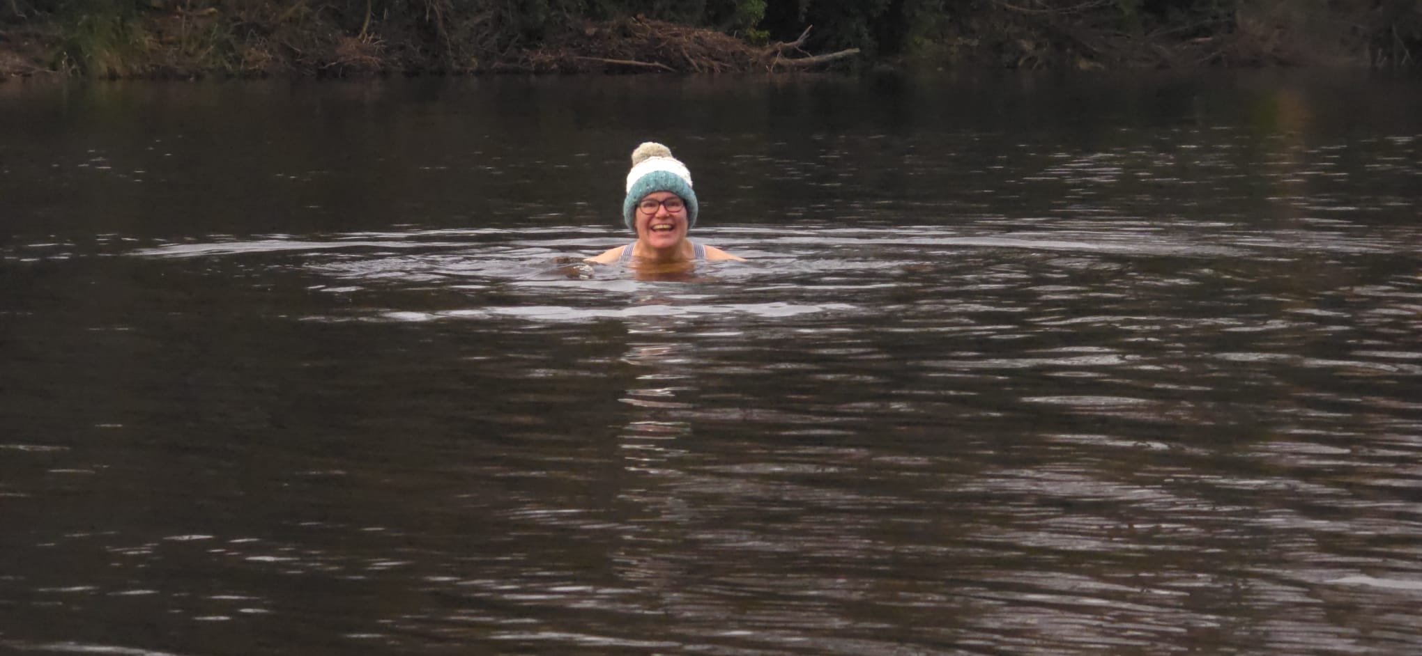 woman swimming in outdoor waters woolley hat with joyful smile